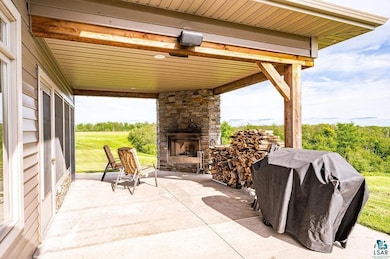 View of patio / terrace featuring an outdoor stone fireplace and grilling area