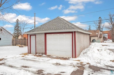 Snow covered garage with a detached garage and fen