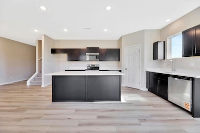 Kitchen with recessed lighting, stainless steel appliances, light wood finished floors, and a kitchen island
