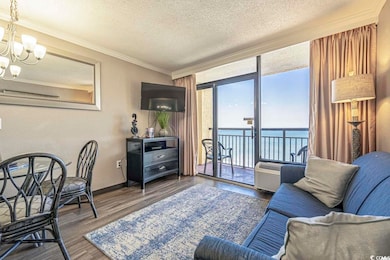 Living area with a textured ceiling, a chandelier, dark wood-type flooring, baseboards, and ornamental molding