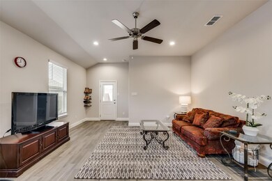 Living room featuring ceiling fan, light hardwood / wood-style floors, and vaulted ceiling