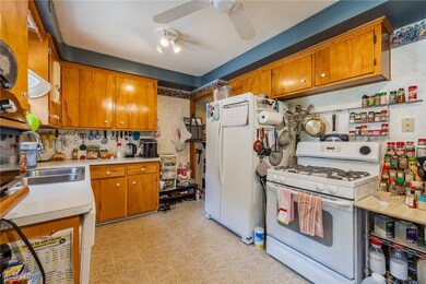 Kitchen featuring white appliances, light floors, light countertops, brown cabinets, and a ceiling fan