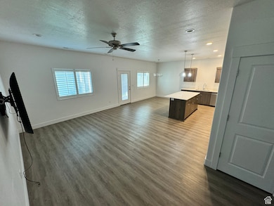 Unfurnished living room featuring a textured ceiling, ceiling fan, wood finished floors, and recessed lighting