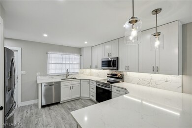 Kitchen with appliances with stainless steel finishes, a sink, light stone counters, and tasteful backsplash