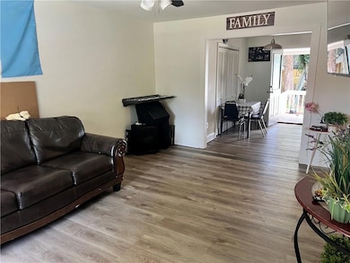 Living room with wood finished floors, ceiling fan, baseboards, and a wood stove