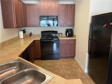 Kitchen with black appliances, a sink, light countertops, and baseboards