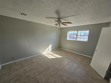 Unfurnished room with a textured ceiling, a ceiling fan, and light tile patterned floors