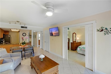 Living room with light tile patterned floors, ceiling fan, and crown molding