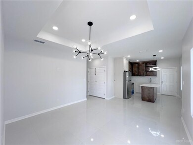 Unfurnished living room featuring a notable chandelier, visible vents, baseboards, and a raised ceiling
