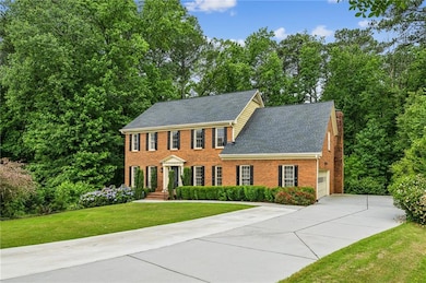 Colonial home with concrete driveway, brick siding, a front yard, a shingled roof, and a chimney