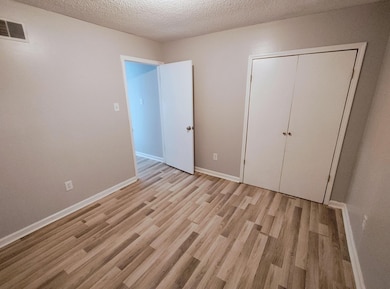 Unfurnished bedroom featuring light wood-style floors, a textured ceiling, and a closet