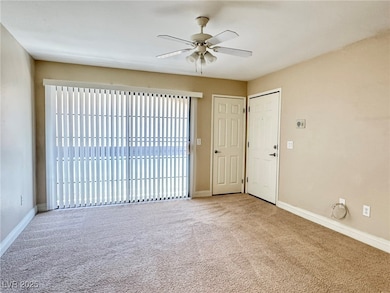 Carpeted spare room with ceiling fan and baseboard