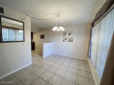 Unfurnished room featuring baseboards, a chandelie