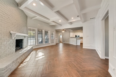 Unfurnished living room with beamed ceiling, a fireplace, ceiling fan, recessed lighting, and brick wall