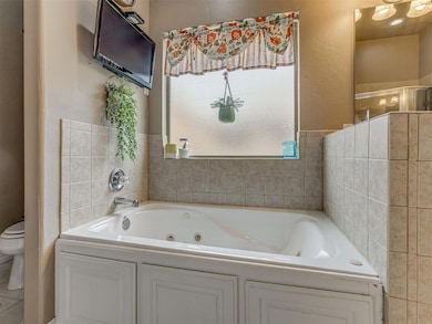 Bathroom with a whirlpool tub, toilet, and a stall shower