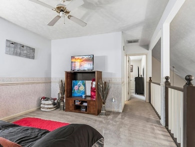 Bedroom featuring carpet flooring, a textured ceiling, a ceiling fan, and wainscoting