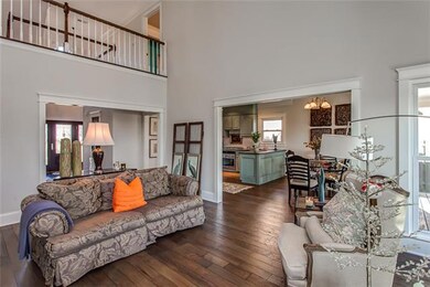 The Great Room view to the front of the home reveals more extensive wood trim revision, an overhead catwalk on the upper level, extended gorgeous hardwoods leading to a spacious redecorated Kitchen & Morning Room...