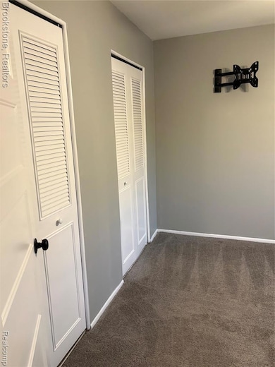 Unfurnished bedroom featuring dark colored carpet and two closets