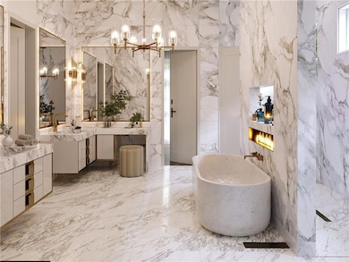 Bathroom with a freestanding bath, vanity, a chandelier, and stone wall