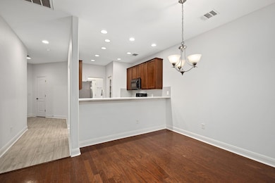 Kitchen with dark wood-style flooring, light countertops, a chandelier, brown cabinetry, and stainless steel appliances