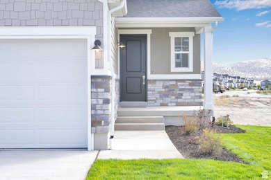 Doorway to property featuring a shingled roof, stone siding, a porch, and a garage
