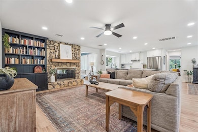 Living room featuring a stone fireplace, healthy amount of natural light, light wood finished floors, recessed lighting, and ceiling fan