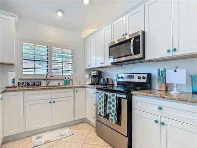 Kitchen with appliances with stainless steel finishes, a sink, light tile patterned floors, light stone counters, and white cabinetry