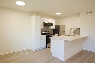 Kitchen with light wood finished floors, backsplas