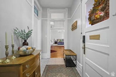 Doorway to outside featuring a chandelier and baseboards