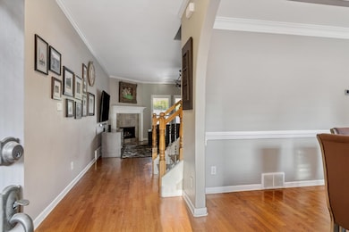 Hall featuring crown molding, wood finished floors, and stairs