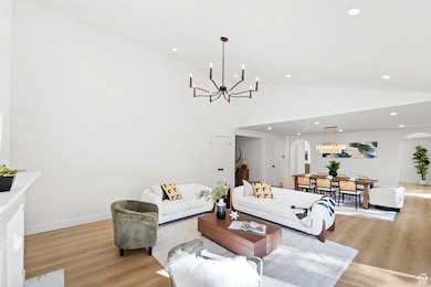 Living area featuring a chandelier, arched walkways, recessed lighting, light wood-type flooring, and high vaulted ceiling