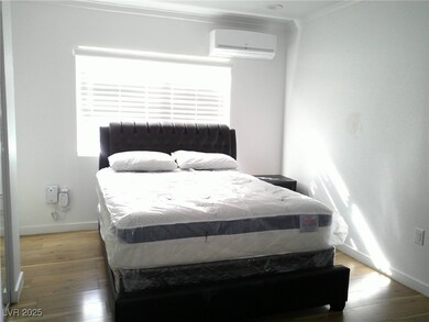 Bedroom with crown molding, a wall unit AC, wood f