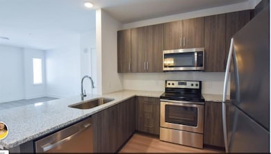 Kitchen featuring light stone countertops, light h