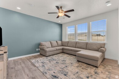 Living room with light wood-style flooring, a ceiling fan, recessed lighting, and a textured ceiling