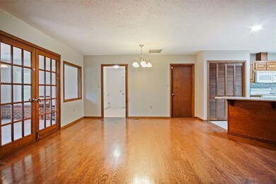 Empty room featuring a notable chandelier, french doors, light hardwood / wood-style floors, and a textured ceiling