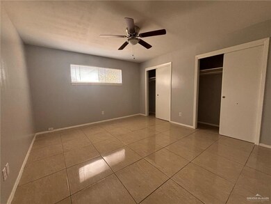 Unfurnished bedroom with two closets, tile patterned floors, baseboards, and ceiling fan