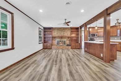 Unfurnished living room with built in shelves, ceiling fan, a fireplace, light wood-style flooring, and recessed lighting