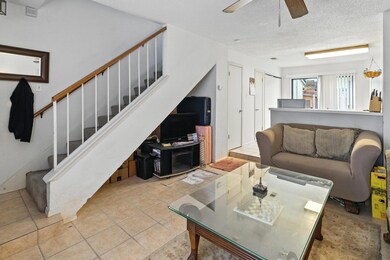 Living area with stairs, ceiling fan, a textured 