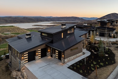 Contemporary home featuring a chimney, a standing seam roof, concrete driveway, and stone siding
