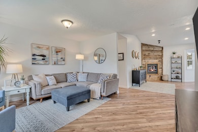 Living room featuring light wood finished floors, a large fireplace, a textured ceiling, lofted ceiling, and recessed lighting