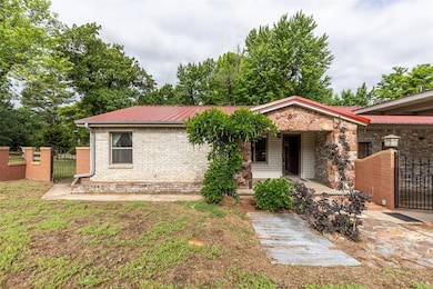 Ranch-style house with a gate, metal roof, a porch, and brick siding