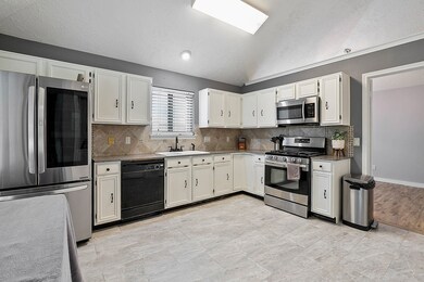 The spacious kitchen features white cabinets, gas range and granite countertops.