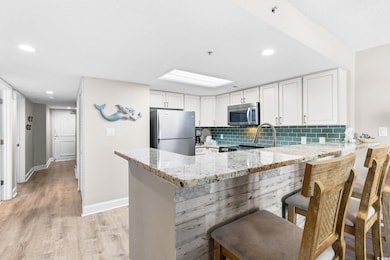 Kitchen with light stone counters, a peninsula, li