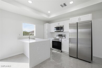 Kitchen with stainless steel appliances, a peninsula, light stone counters, white cabinets, and recessed lighting