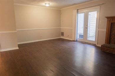 Unfurnished room featuring french doors, dark wood finished floors, ornamental molding, and baseboards