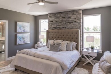 Main Floor Master Bedroom with Stone Accent Wall and Coffered Ceiling