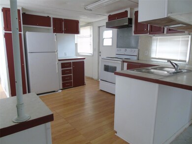 Kitchen with white appliances, exhaust hood, a peninsula, and light wood-style flooring
