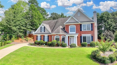 Traditional-style house featuring brick siding, a chimney, and roof with shingles