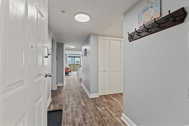 Hallway with baseboards, a textured ceiling, and w