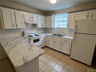 Kitchen featuring white appliances, under cabinet range hood, a sink, a peninsula, and white cabinetry